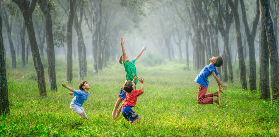Children having fun in nature jumping around in the grass - GapGuru