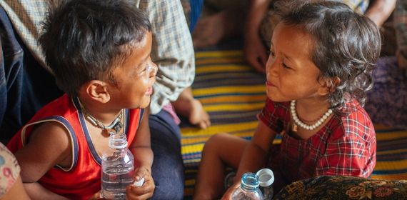 Two kids smiling at each other with bottles of water - GapGuru