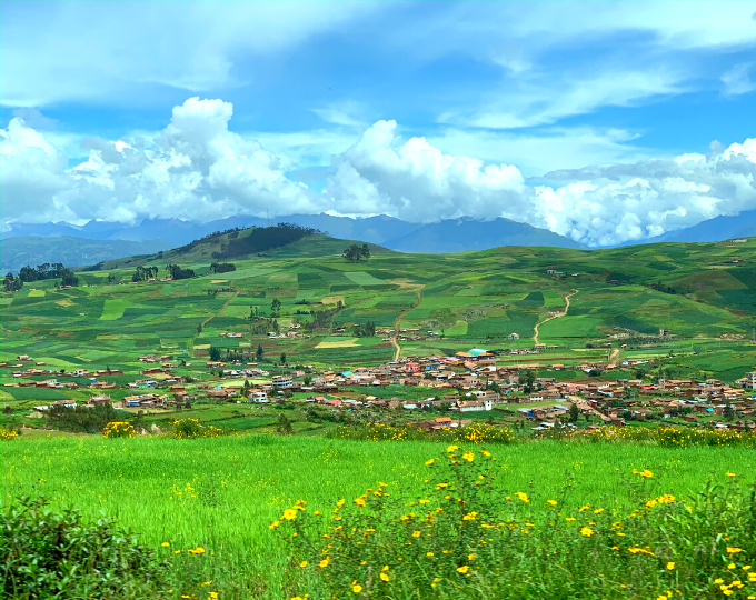 The town of Chinchero, Peru from a distance with rolling green hills around it - GapGuru