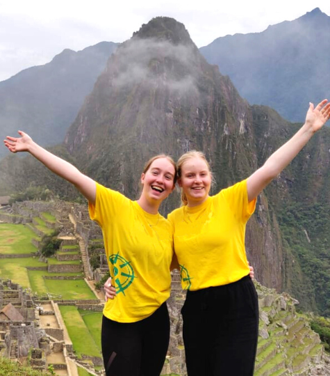 Two GapGuru gap year students at machu Picchu in Peru with their hands up and smiling - GapGuru