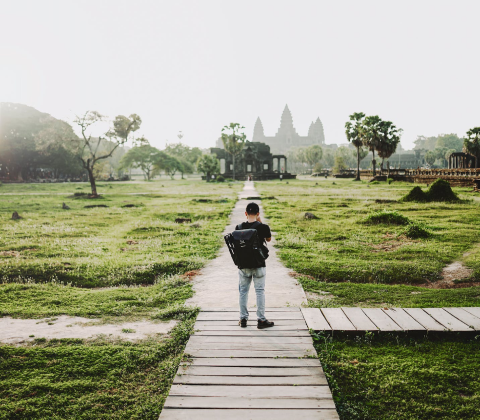 GapGuru team member sight seeing walking on a wooden walkway with the Angkor Wat temple in the distance