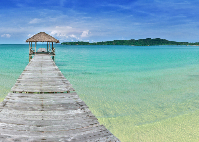 A pier with a small wooden hut on azure waters and a white sand beach in southern Cambodia - Gapguru