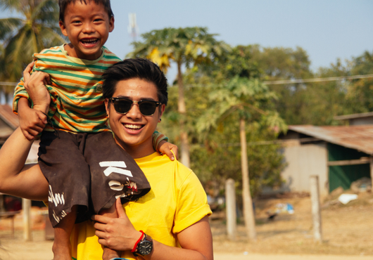 GapGuru team member with a child on his shoulder in Cambodia