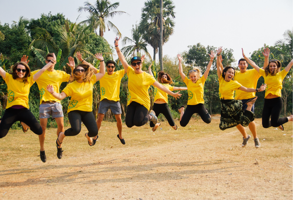 A group of Gap Year students wearing yellow t-shirts jumping in the air - GapGuru