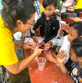 A GapGuru gap year student showing school kids an experiment with straws, cups and water - GapGuru