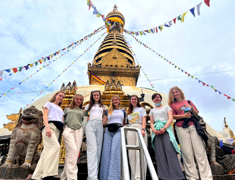 Six GapGuru Gap Year students standing in front of a Nepalese shrine with colourful flags - GapGuru